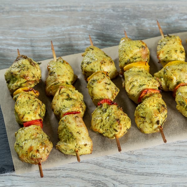 Goodi's Greek chicken souvlaki skewers with bell peppers on parchment paper.