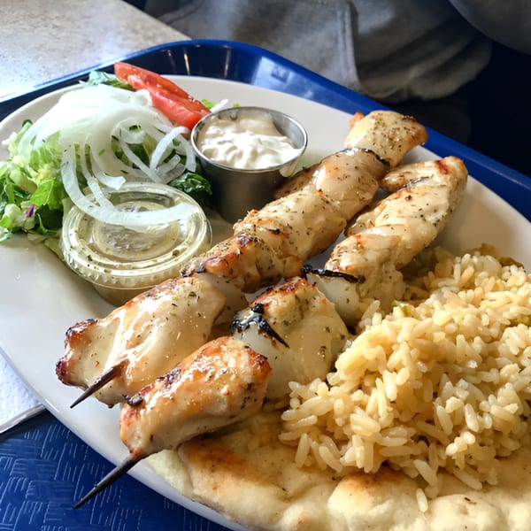 Goodi's Greek chicken souvlaki with rice, salad, pita bread, and tzatziki sauce.